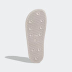View of the outsole of the Adidas Adilette Slides Unisex in pink, showing the durable rubber sole and textured tread pattern.