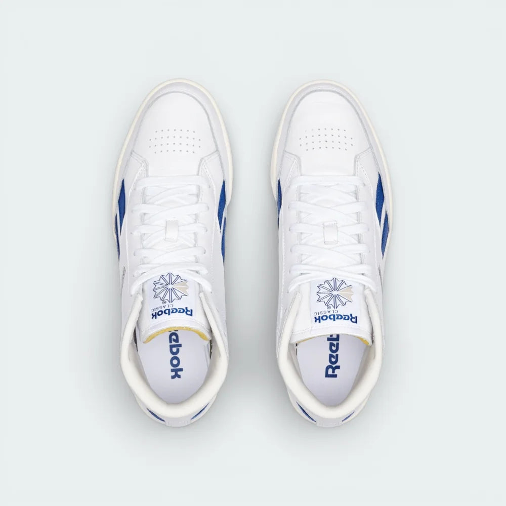 Top-down view of the white leather trainers, highlighting the exposed foam tongue and the clean, traditional lacing system.