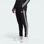 Side profile of the black Adidas Tiro 23 training pants, showcasing the slim tapered fit and the iconic white Three Stripes.