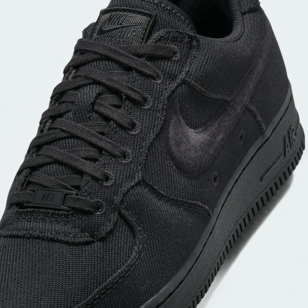 Close-up zoom on the front of the Nike Air Force 1 Low Canvas Men's trainers, showing the canvas upper texture, perforated toe box, and lacing system.