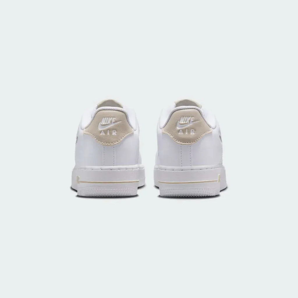 Rear view of the Nike Air Force 1 Low Juniors' white/sand trainers, focusing on the heel panel and Nike Air branding.