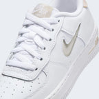 Close-up zoom on the front of the Nike Air Force 1 Low Juniors' white/sand trainers, showing the perforated toe box, lacing system, and texture of the leather upper.