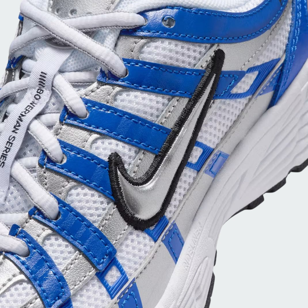 Close-up zoom on the front of the Nike P-6000 Juniors' blue trainers, showing the intricate mesh base, metallic overlays, and lacing system.