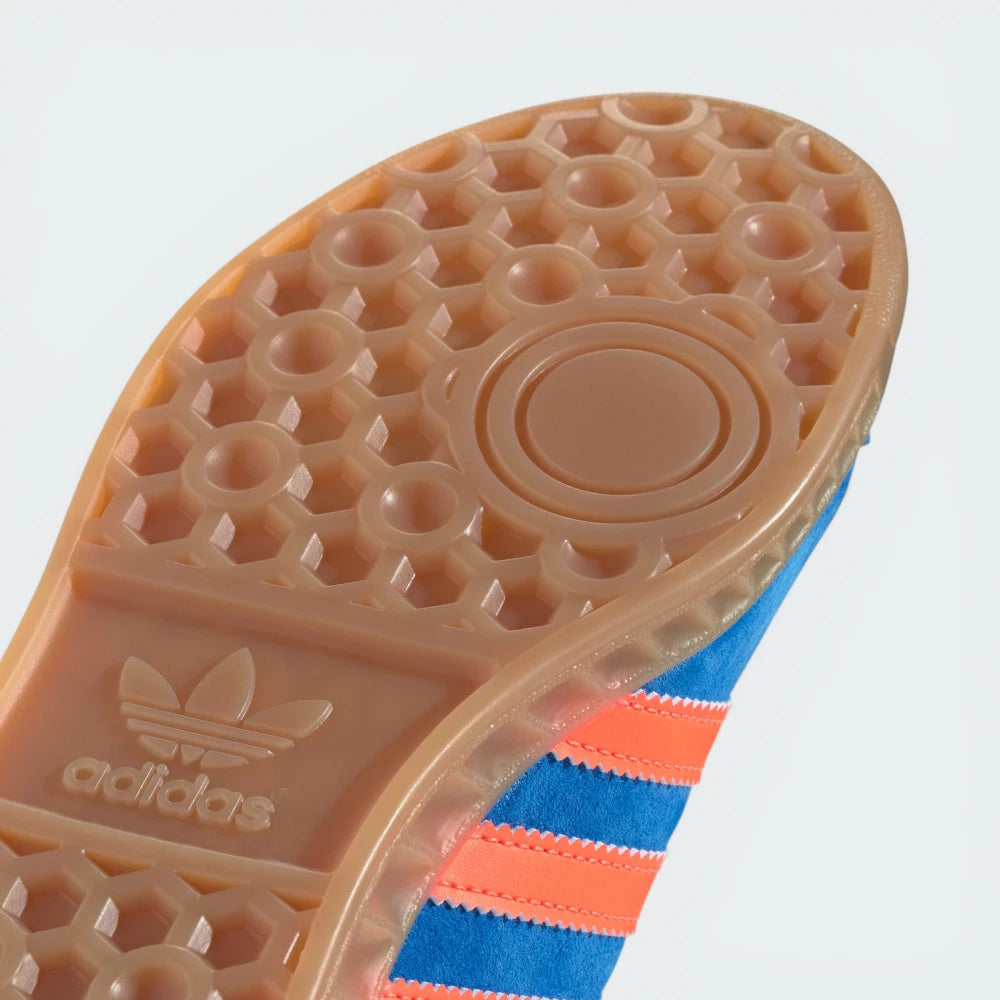 Close-up of an Adidas shoe sole with a blue and orange striped laces on a light gray background