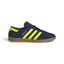 Highlights the sleek low-profile lateral silhouette featuring the rich Night Indigo suede upper, vibrant Solar Yellow leather serrated 3-Stripes, metallic gold foil "HAMBURG" script, matching yellow heel tab, and semi-translucent gum rubber cupsole with debossed adidas Trefoil branding.