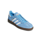 Angle View Showing Both Pair Side by Side: Three-quarter front angle of the light blue suede sneaker highlighting the white serrated stripes, T-toe overlay, and dark gum midsole.