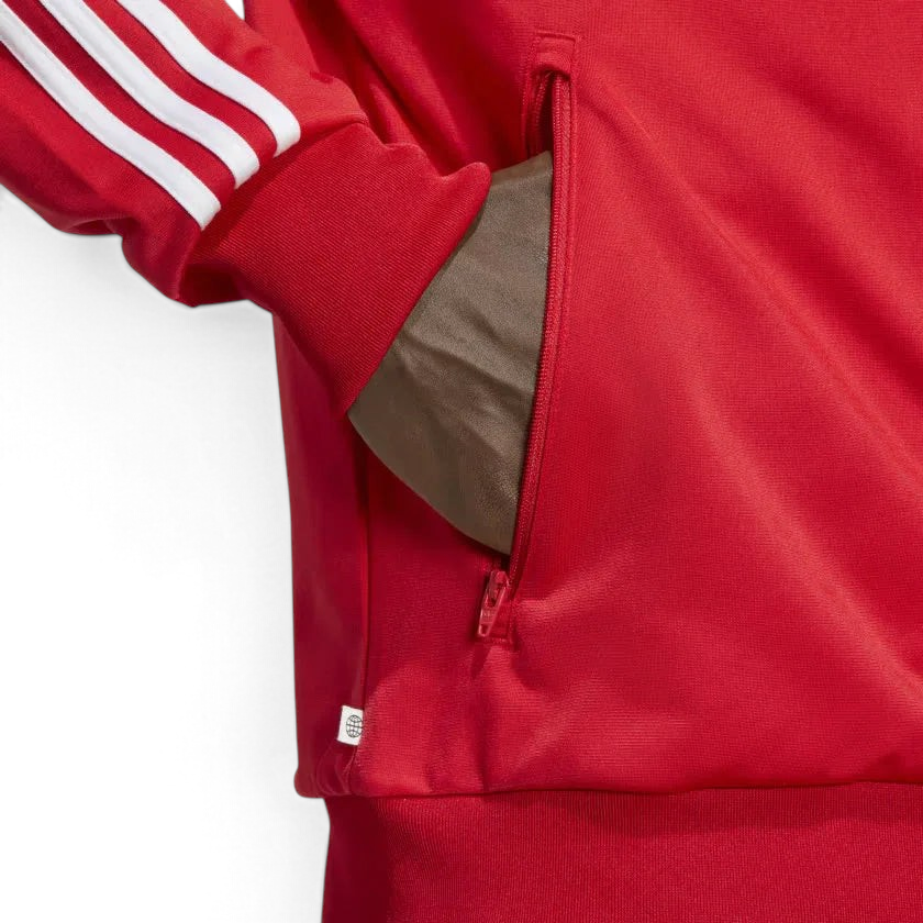 Firebird red jacket model demonstrating the zipped pocket and tag that shows recycled material