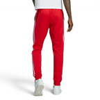 Adidas Superstar Track Pants Men's in red, back view showcasing the tapered leg fit and ribbed cuffs.