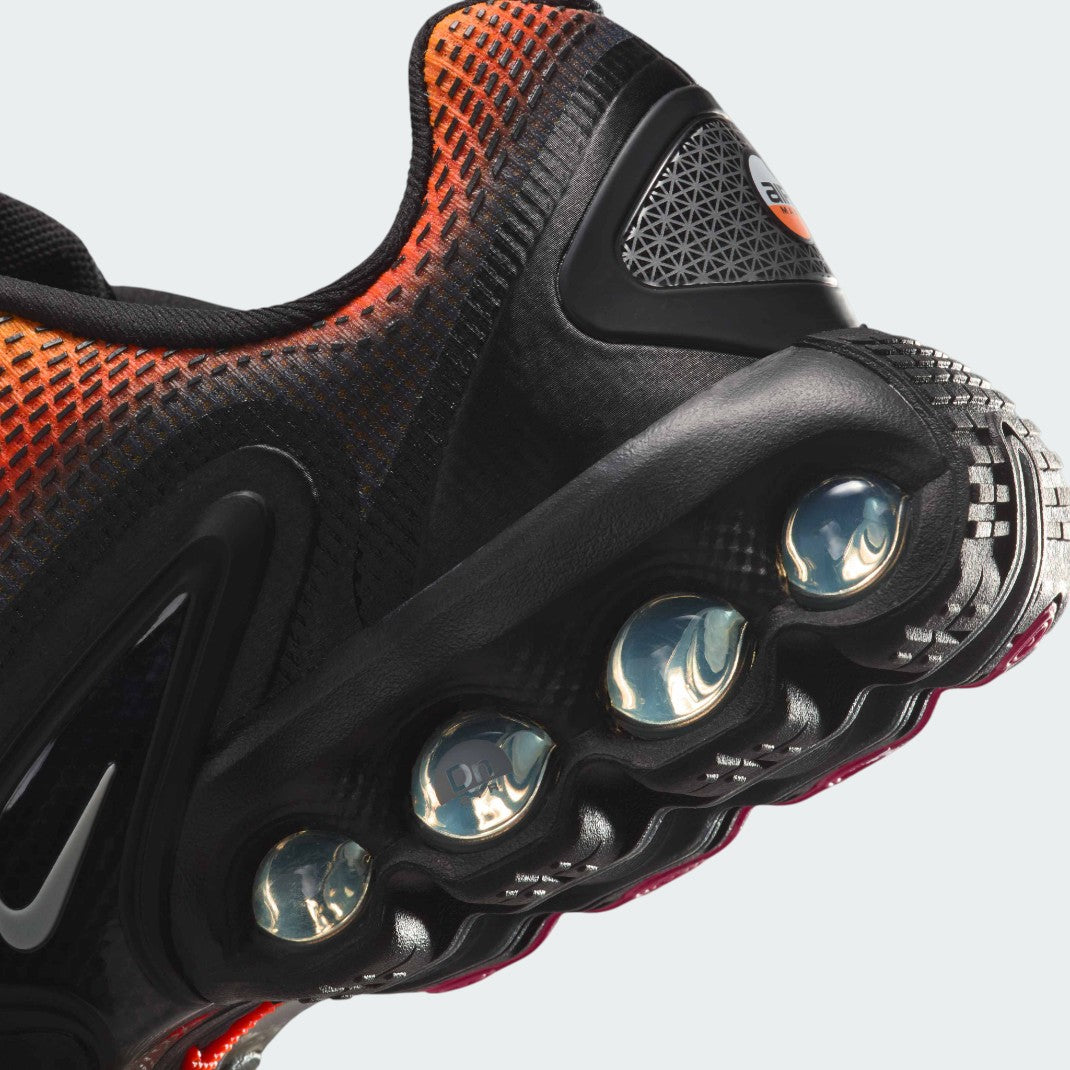 Detailed zoom on the outsole and midsole of the Nike Air Max DN Juniors' black running trainers, highlighting the dual-pressure Dynamic Air cushioning system and robust rubber outsole.