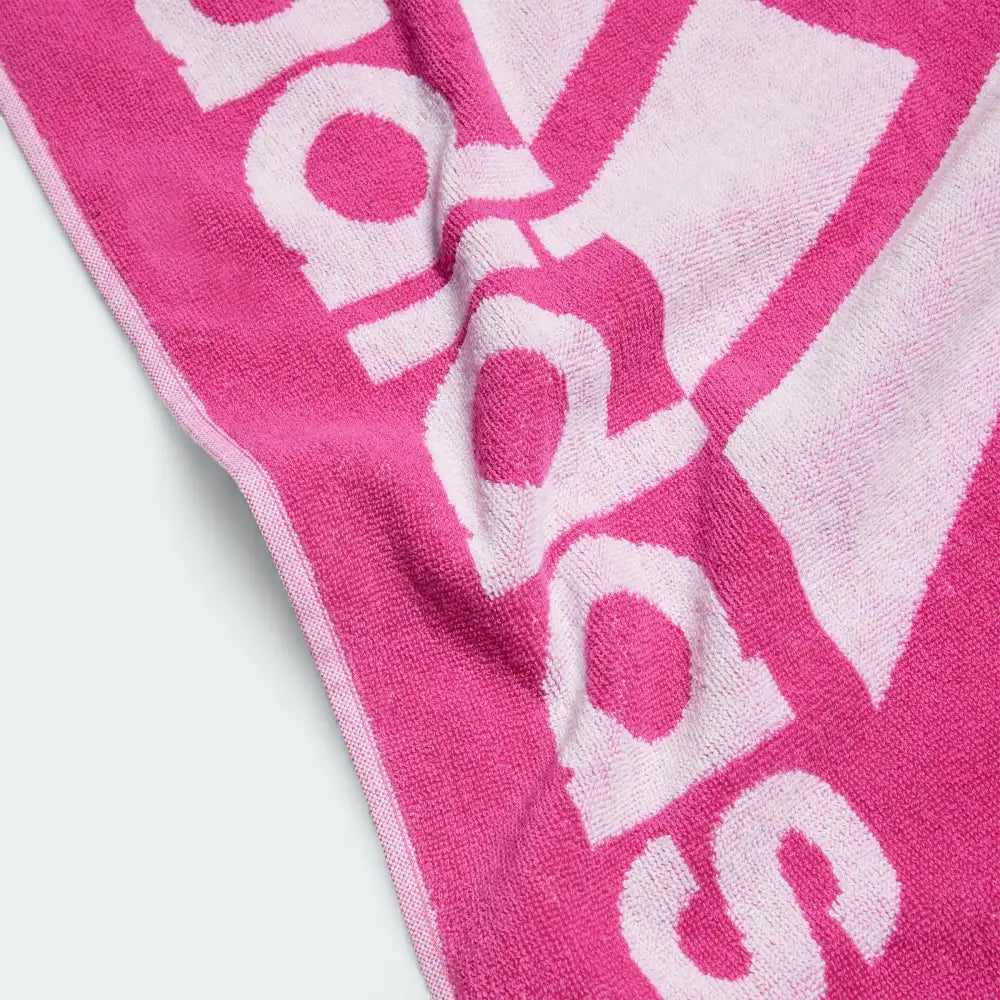 Detailed view of a corner of the Adidas Cotton Sports Towel in pink, highlighting the stitched edges and the embroidered Adidas logo.