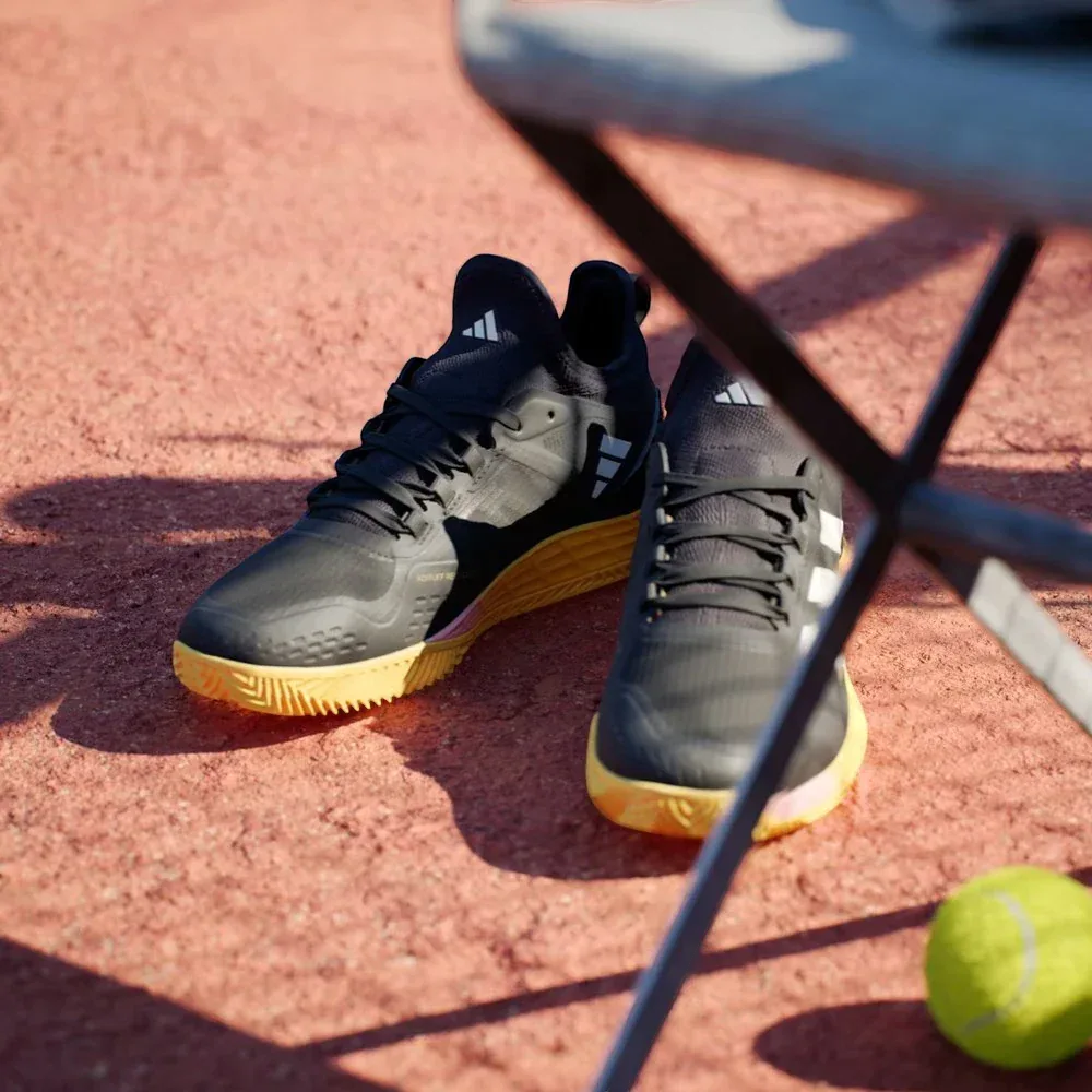 Angled shot of both Adizero Ubersonic 4.1 shoes, showcasing the sleek, modern silhouette and the metallic branding details.