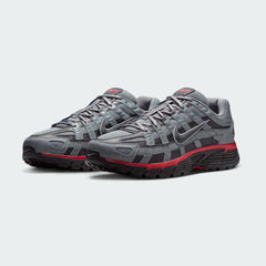 Angled view of two Nike P-6000 SE men's trainers in grey and black, side by side, showcasing their chunky, retro-inspired aesthetic and layered construction.