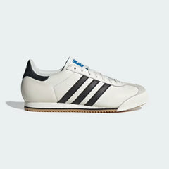 The Core White K 74, highlighting the clean black 3-Stripes and the slim, low-profile athletic silhouette.