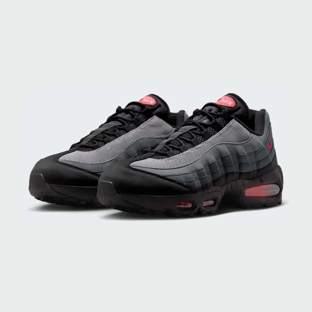 Angled view of two Nike Air Max 95 OG Men's running shoes in black and crimson red, side by side, showcasing their timeless design and layered upper.