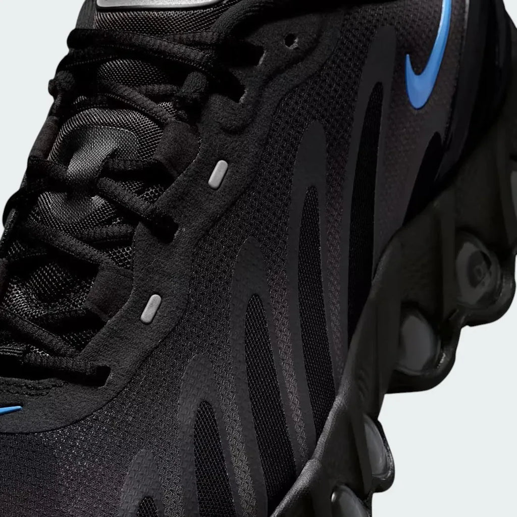 Close-up zoom on the front of the Nike Air Max DN Men's black running shoes, showing the mesh upper texture, haptic print details, and lacing system.