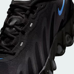 Close-up zoom on the front of the Nike Air Max DN Men's black running shoes, showing the mesh upper texture, haptic print details, and lacing system.