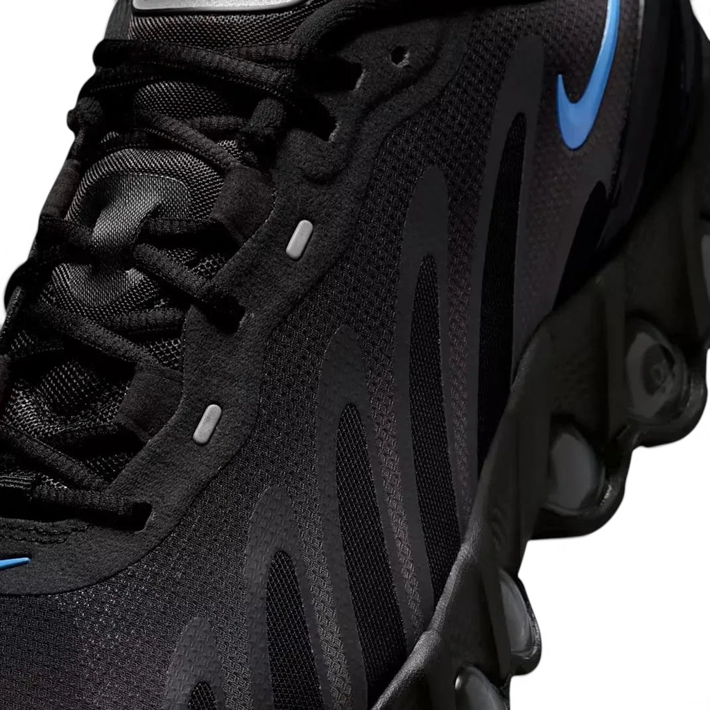 Close-up zoom on the front of the Nike Air Max DN Men's black running shoes, showing the mesh upper texture, haptic print details, and lacing system.