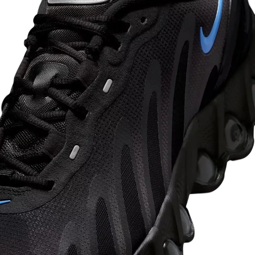 Close-up zoom on the front of the Nike Air Max DN Men's black running shoes, showing the mesh upper texture, haptic print details, and lacing system.