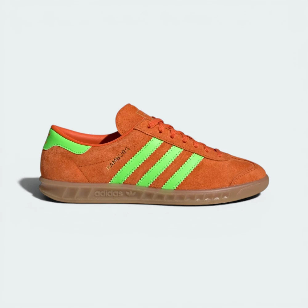 Side profile of the Orange Adidas Hamburg, highlighting the Solar Green Three Stripes and the translucent gum rubber sole.