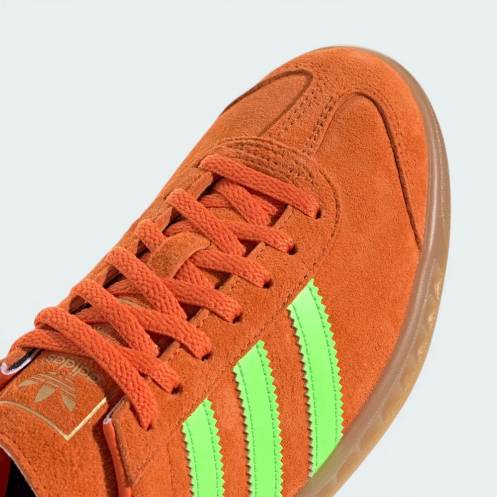 Close-up of the toe box and side panels, highlighting the precision stitching and the contrast between the orange and green materials.