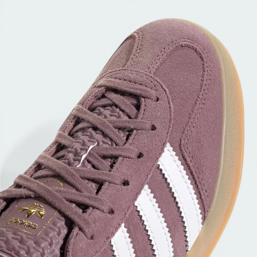 Close-up of the tongue, highlighting the gold Trefoil logo and the fine texture of the plum suede.
