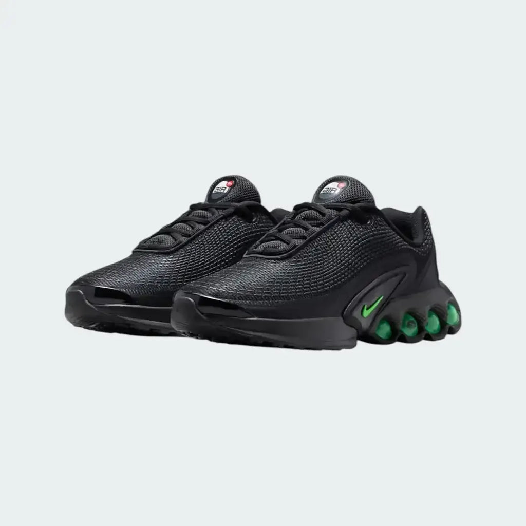 Angled view of two Nike Air Max DN Juniors' black running trainers, side by side, showcasing their bold, modern design and prominent Air unit.