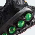 Detailed zoom on the outsole and midsole of the Nike Air Max DN Juniors' black running trainers, highlighting the dual-pressure Dynamic Air cushioning system and robust rubber outsole.