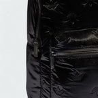 Close-up zoom on the fabric of the Adidas Puffy Satin Backpack in black, showing the smooth, slightly glossy satin texture and quilted effect.