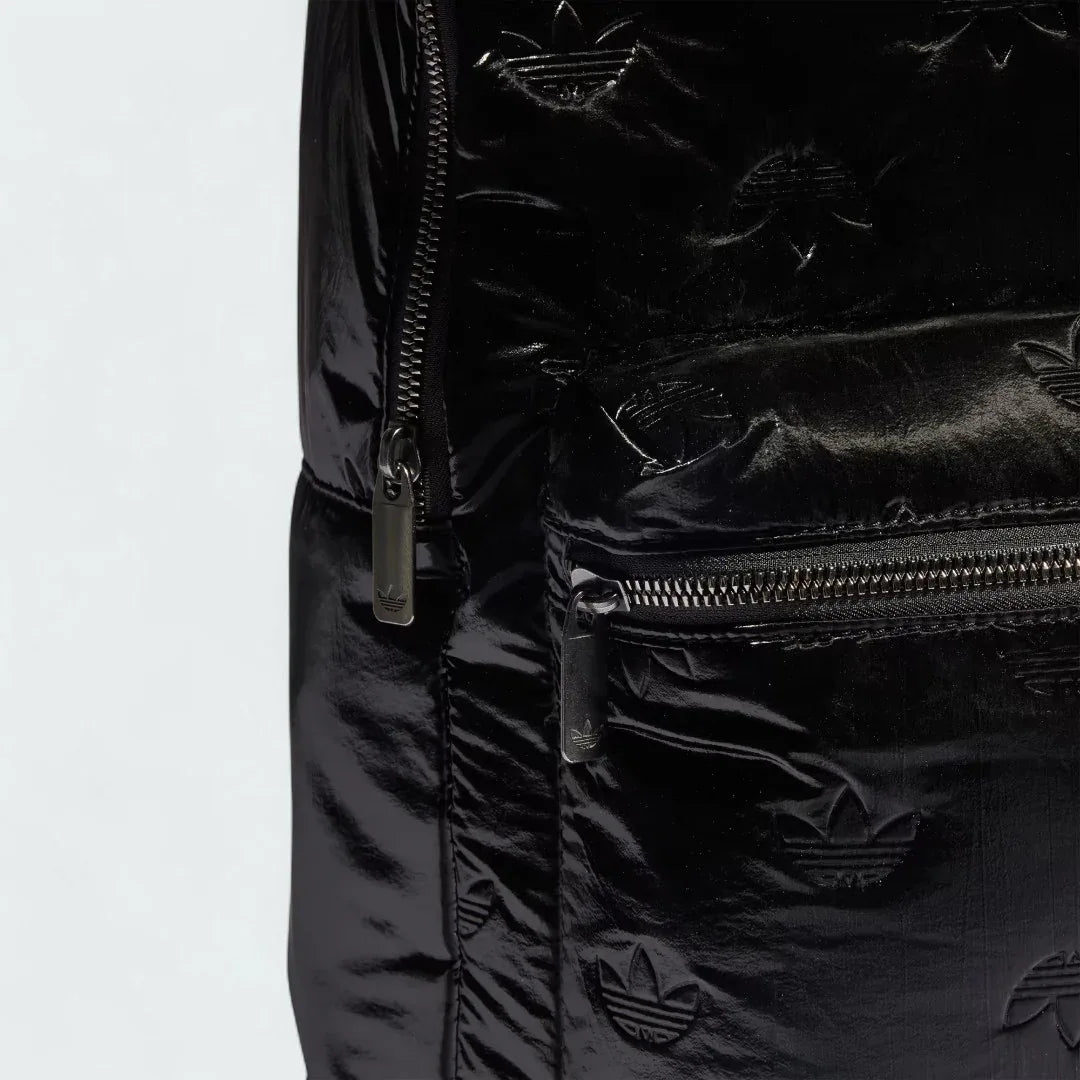 Close-up zoom on the fabric of the Adidas Puffy Satin Backpack in black, showing the smooth, slightly glossy satin texture and quilted effect.