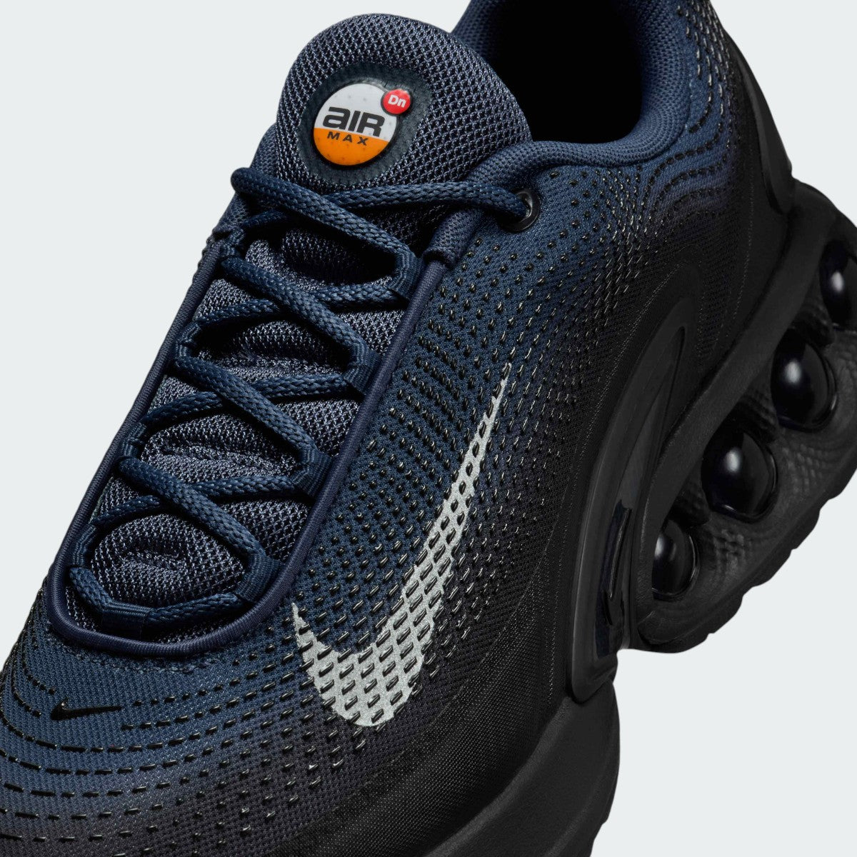 Close-up zoom on the front of the Nike Air Max DN Men's dark navy running shoes, showing the mesh upper texture, haptic print details, and lacing system.