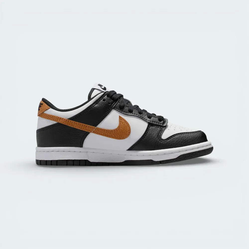 Side profile of the Nike Dunk Low Juniors in Black/White, showing the iconic leather overlays and the clean white midsole.
