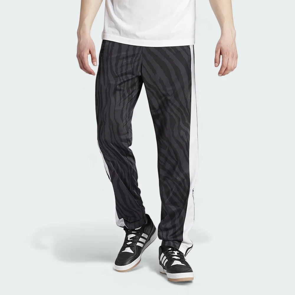 Adidas Adibreak Button Track Pants in black with a subtle animal print, front view showing the elastic drawcord waist and the full line of snap buttons down the side.