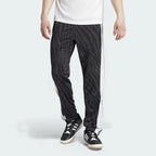 Adidas Adibreak Button Track Pants in black with a subtle animal print, front view showing the elastic drawcord waist and the full line of snap buttons down the side.