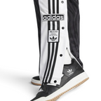 Adidas Adibreak Button Track Pants in black with some side snaps undone, showing the exposed contrasting material underneath and the "breakaway" style.