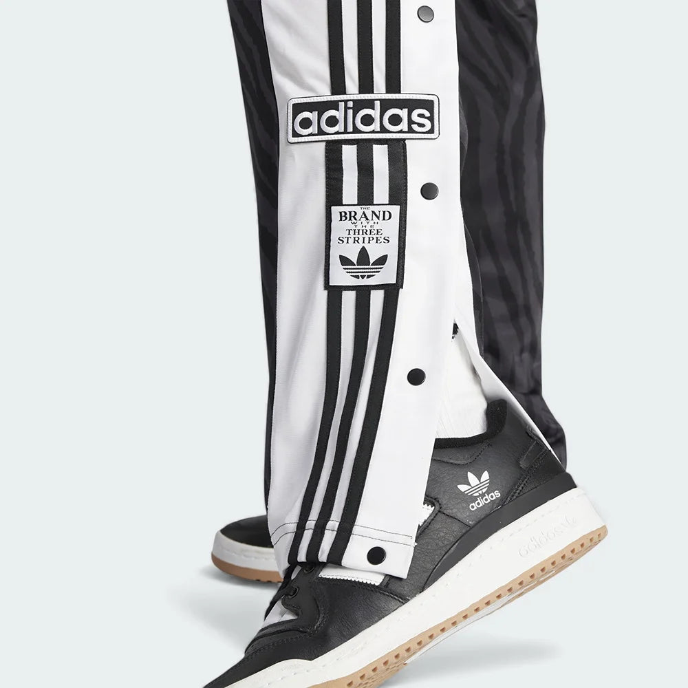 Adidas Adibreak Button Track Pants in black with some side snaps undone, showing the exposed contrasting material underneath and the "breakaway" style.