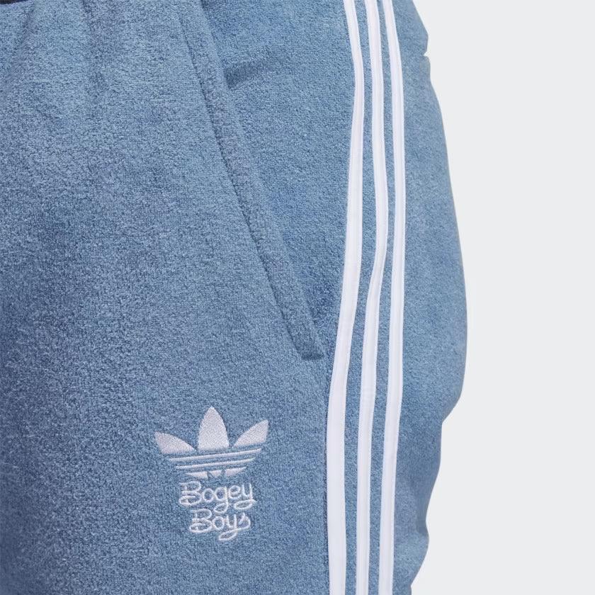 Close-up zoom on the fabric of the Adidas x Bogey Boys Golf Track Pants in blue, showing the texture and the embroidered Trefoil/Bogey Boys logo detail.