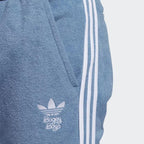 Close-up zoom on the fabric of the Adidas x Bogey Boys Golf Track Pants in blue, showing the texture and the embroidered Trefoil/Bogey Boys logo detail.