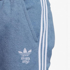 Close-up zoom on the fabric of the Adidas x Bogey Boys Golf Track Pants in blue, showing the texture and the embroidered Trefoil/Bogey Boys logo detail.