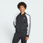 Highlights the high-velocity sweep of the white 3-Stripes running down the sleeves, showing the professional, deep matte black interlock fabric and the crisp white embroidered Trefoil logo.