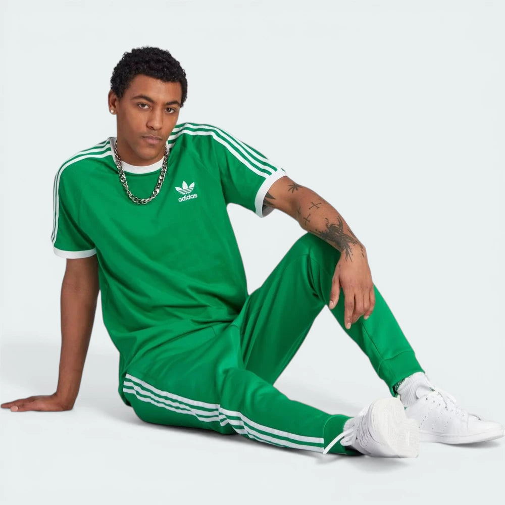 Person wearing a green Adidas tracksuit on a white background