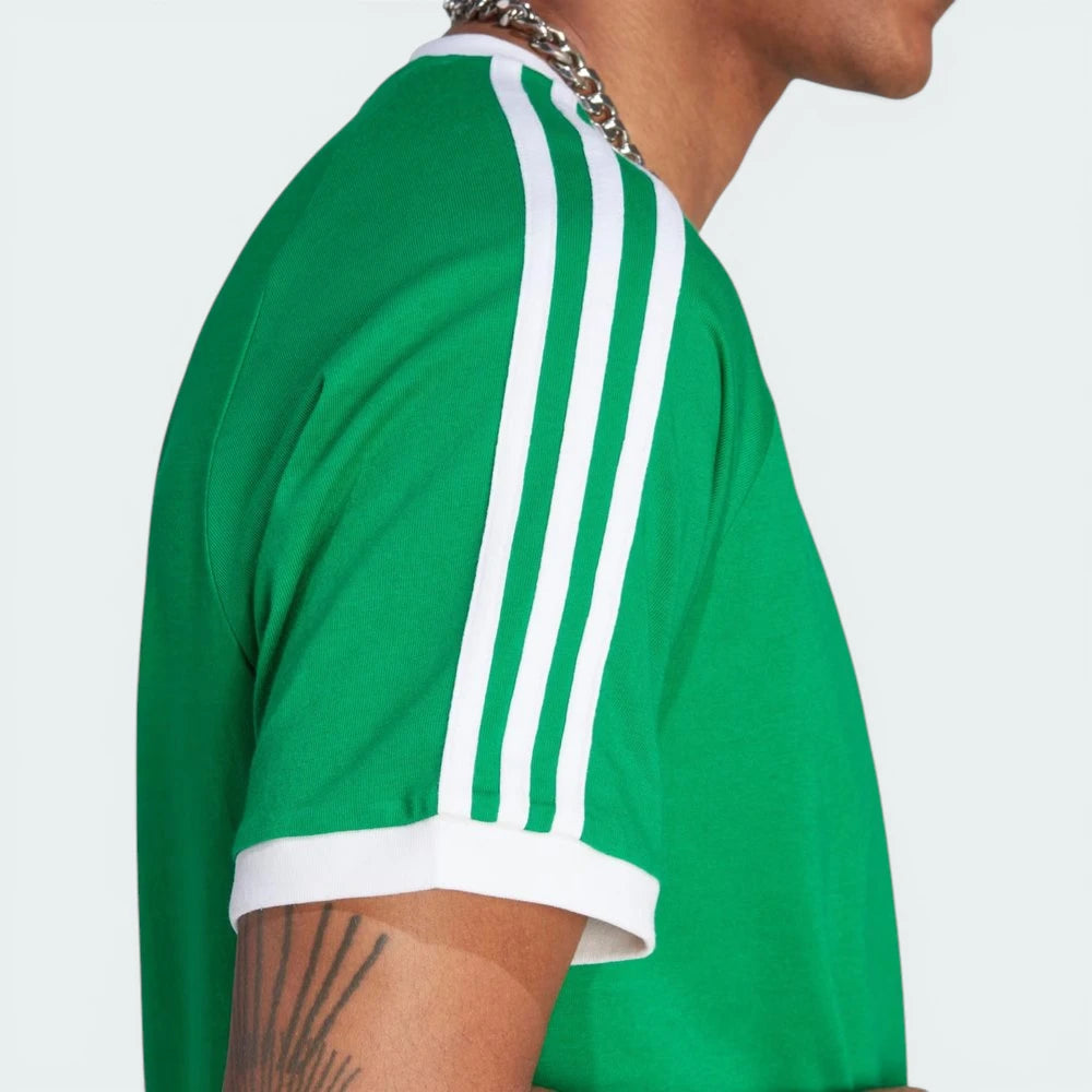 Side profile of the green Adicolor Sport t-shirt, showcasing the iconic white 3-Stripes running from the shoulder to the sleeve hem.