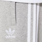 Close-up of the upper thigh area, focusing on the high-quality embroidery of the Trefoil logo and the secure zip pocket detail.