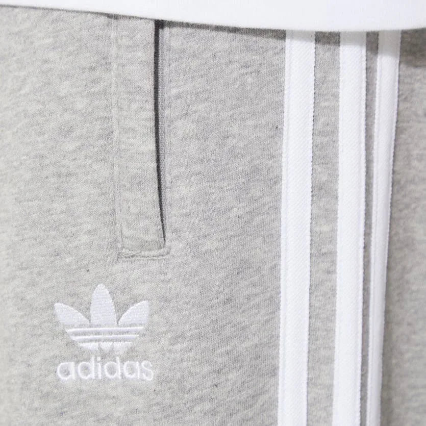 Close-up of the upper thigh area, focusing on the high-quality embroidery of the Trefoil logo and the secure zip pocket detail.