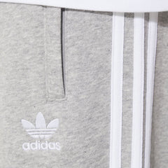 Close-up of the upper thigh area, focusing on the high-quality embroidery of the Trefoil logo and the secure zip pocket detail.