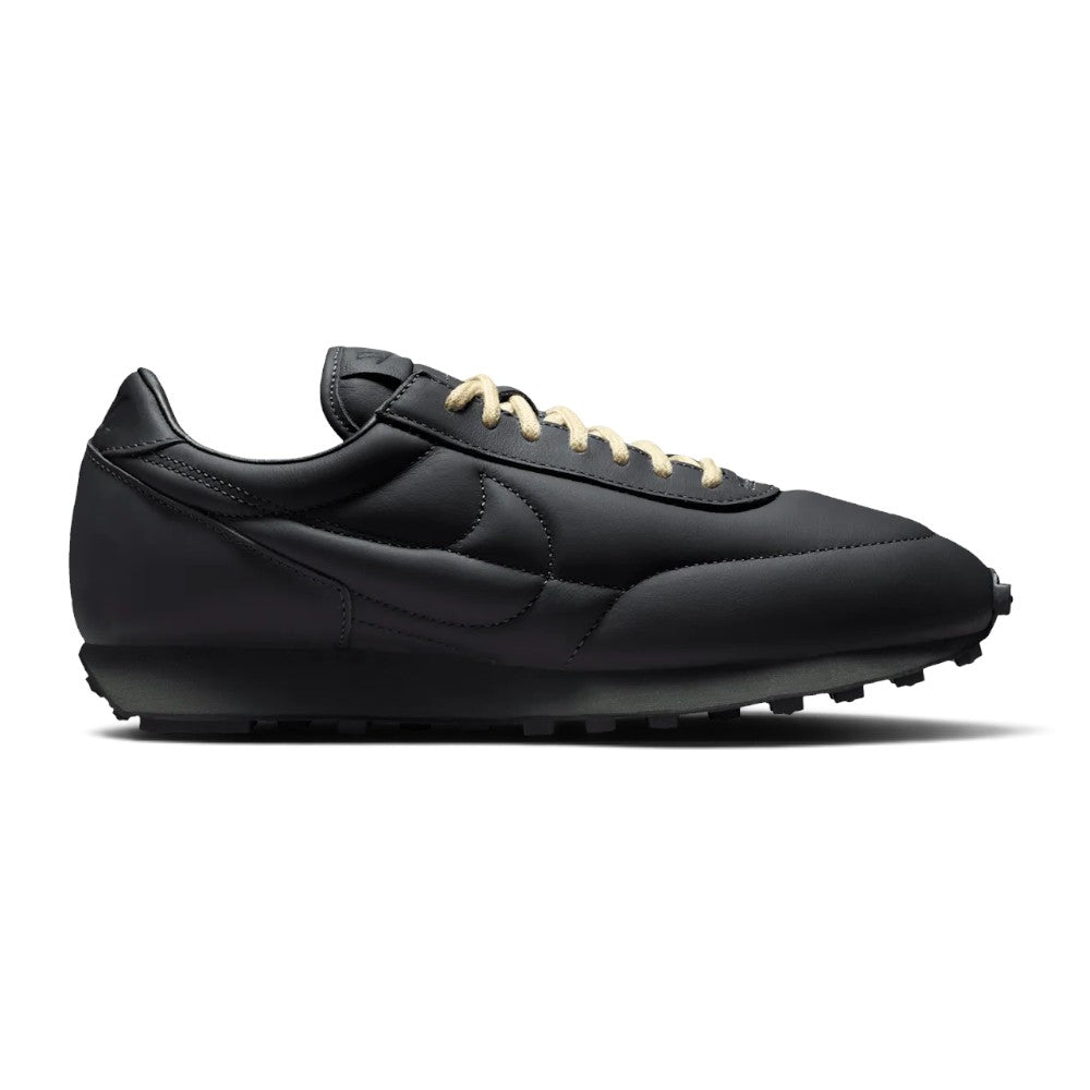 Capturing the 1970s low-profile track silhouette, detailing the anthracite stuffed leather upper, light bone leather overlays, crisp sidewall Swoosh, vintage sail foam wedge midsole, and studded black rubber waffle outsole edge.