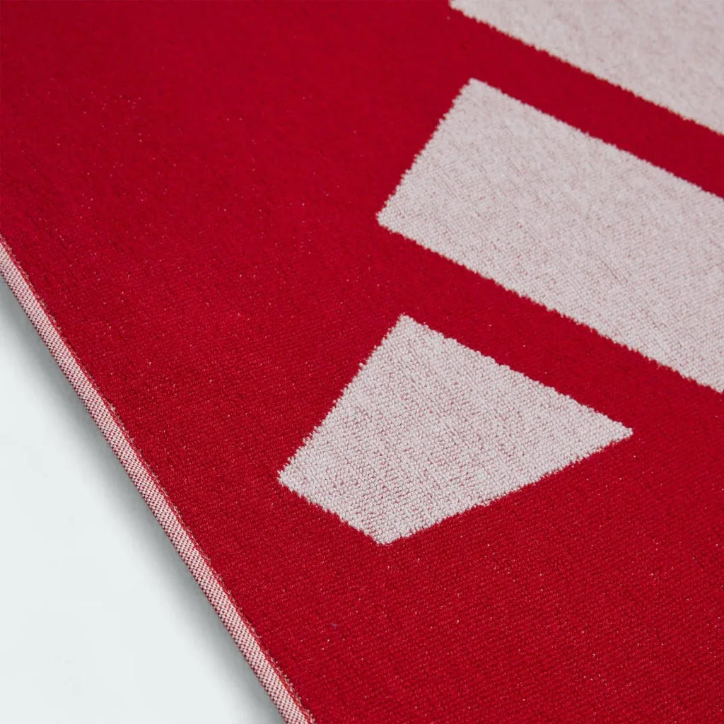 Detailed view of a corner of the Adidas Cotton Towel in red, highlighting the stitched edges and the embroidered Adidas logo.