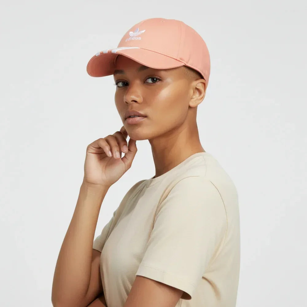 Person wearing a peach-colored cap with a brand logo on a light gray background Main image
