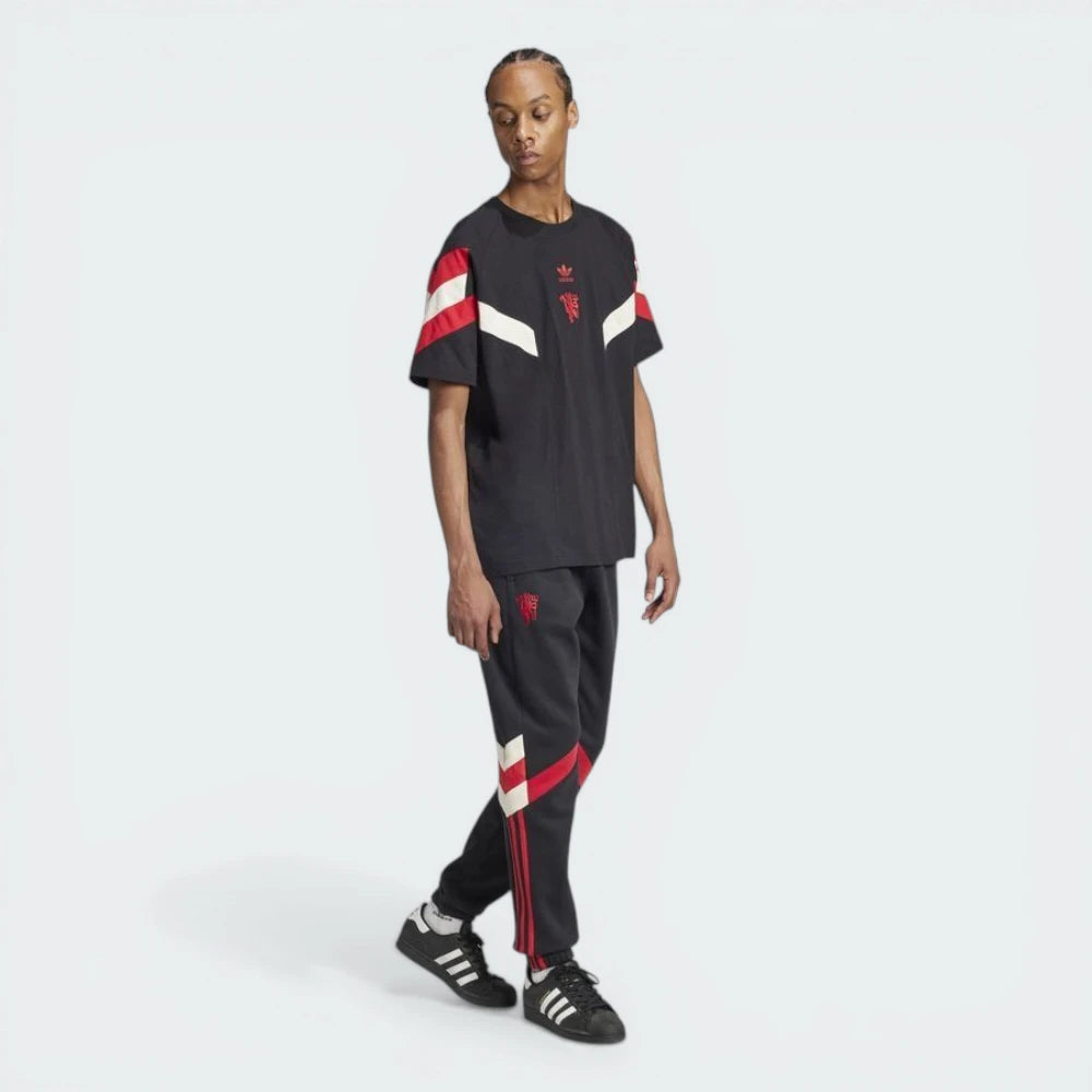 Person wearing a black Adidas tracksuit with red and white accents on a white background
