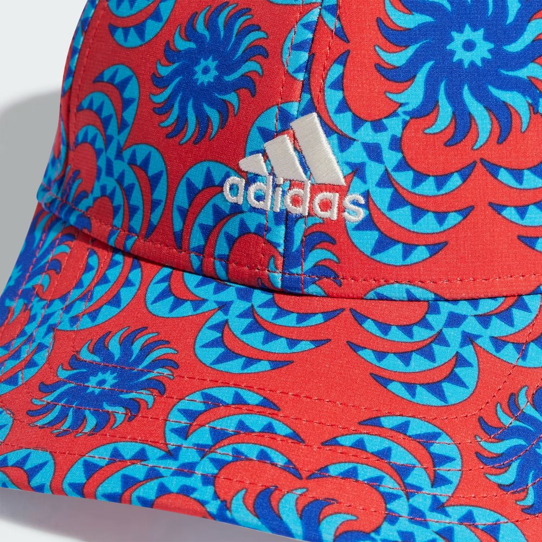 Close-up zoom on the fabric of the Adidas x Farm Rio cap, showing the intricate, colourful graphic print and the texture of the recycled polyester material.