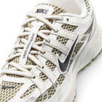 Details the micro-precision of the forefoot area, showing the breathable olive mesh toe box, synthetic leather toe bumper, tonal laces, and branded tongue patch.